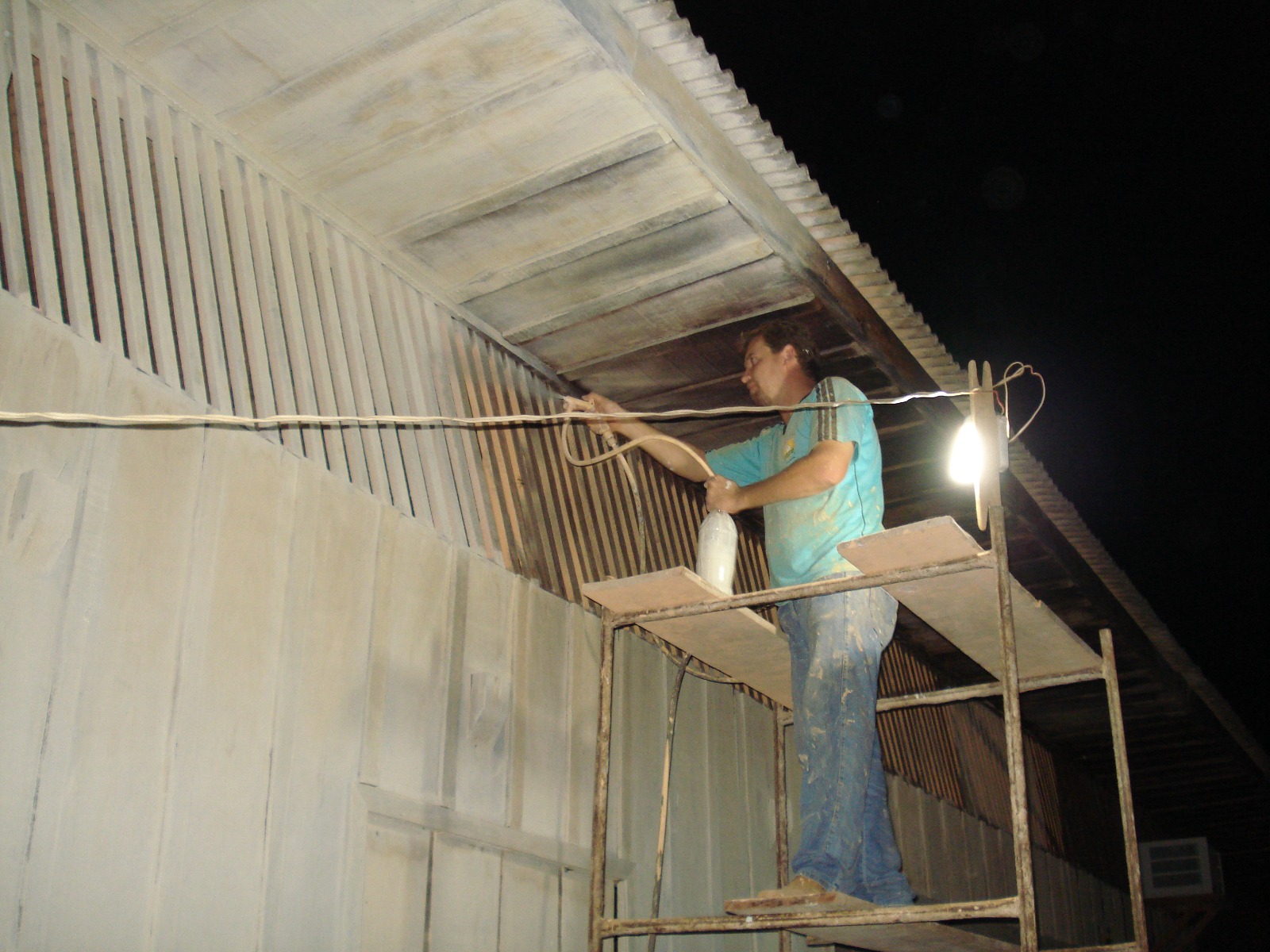 Trabalhador pintando o forro do prédio à noite