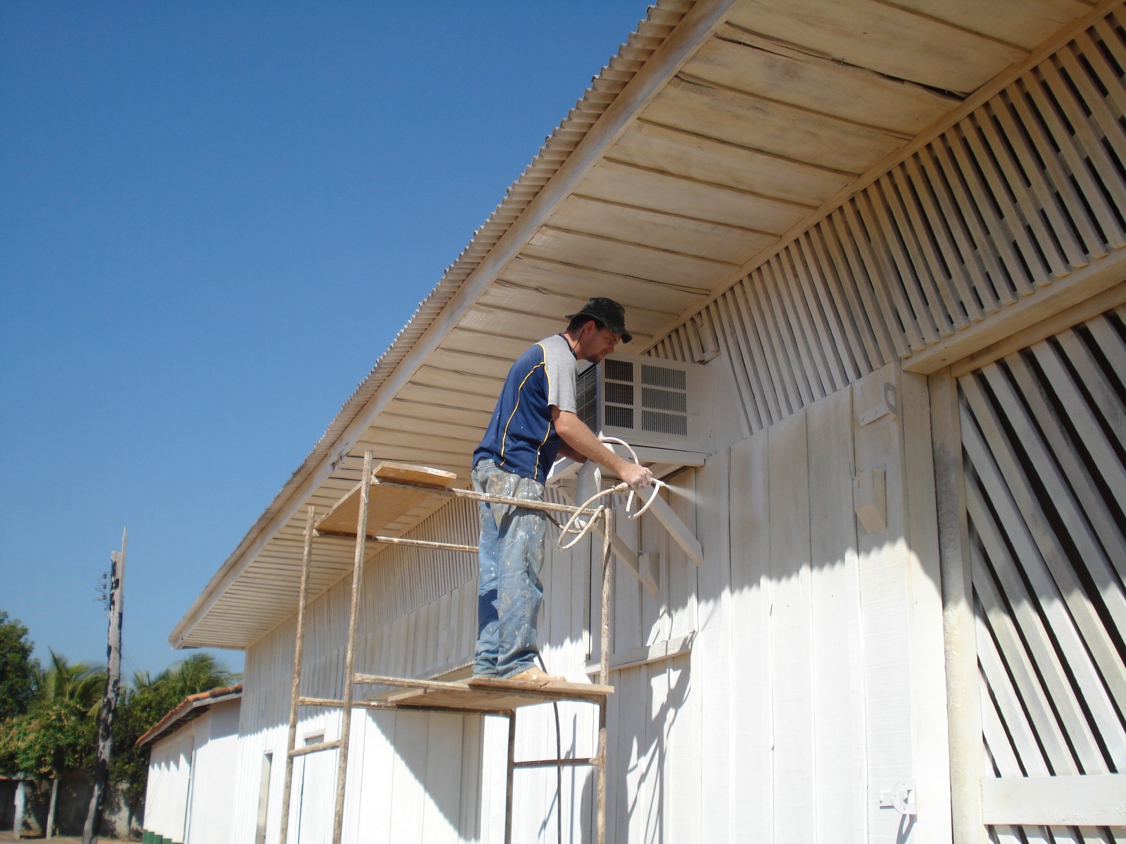 Trabalhador pintando a fachada da Escola Agrícola Terra Nova